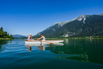 Eine Familie macht eine Bootstour mit einem Paddelboot auf dem idyllischen Weißensee nahe des Familienhotels Ramsi