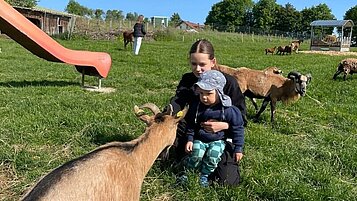 Zwei Kinder streicheln die Ziegen im Streichelzoo des Familienhotels Der Böhmerwald.