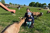 Zwei Kinder streicheln die Ziegen im Streichelzoo des Familienhotels Der Böhmerwald.