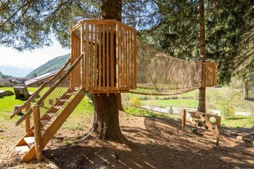 Abenteuerspielplatz mit Baumhaus, Hängebrücke und Zielwurfspiel im Wald des Familienhotels Huber in Südtirol