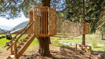 Abenteuerspielplatz mit Baumhaus, Hängebrücke und Zielwurfspiel im Wald des Familienhotels Huber in Südtirol