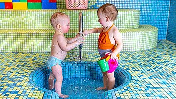 Babys im Babyschwimmbecken mit Wasserspielsachen im Familienhotel Elldus Resort im Erzgebirge