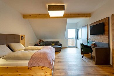 Doppelbett im Familienzimmer mit einer Wohnecke im Familienhotel Familien Resort Petschnighof in Tirol
