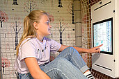 Mädchen spielt auf dem Indoor Spielplatz des Familienhotels Rhön Feeling auf einem Display.