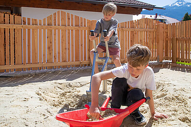 Zwei Jungs spielen auf dem Outdoor Spielplatz des Familienhotels Tirolerhof im Sand.