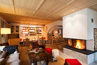 Kaminlounge mit Bar und gemütlichen Sitzbereichen im Familienhotel Bella Vista in Südtirol.