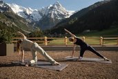 Yoga auf der Terrasse des Familienhotel Bella Vista in Südtirol mit Blick auf Wiesen, Berge und verschneite Gipfel.