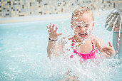 Kleines Mädchen planscht im Kinderbecken des Schwimmbads im Familienhotel Landgut Furtherwirt in Tirol.