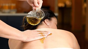Wellness im Salzburger Land: Frau genießt eine Massage mit Ölen.