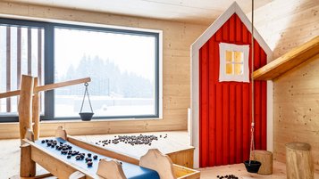 Spielbereich mit Holzelementen und Kastanien im neuen Erlebnishof im Allgäuer Berghof