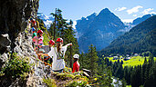 Kinder klettern an einer Steinwand hoch.