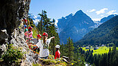 Kinder klettern an einer Steinwand hoch.