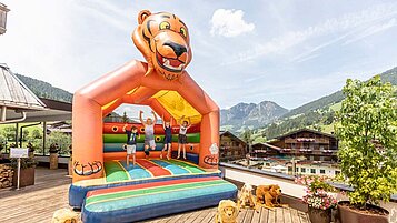 Kinder hüpfen auf der großen Hüpfburg vom Familienhotel Galtenberg Family & Wellness Resort in Tirol.