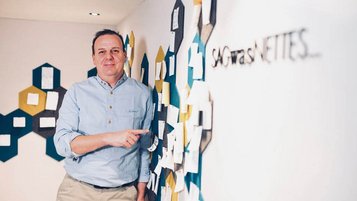 Gastgeber Klaus vom Familienhotel Kindl zeigt auf eine Wand voller Gästebotschaften im Hotel.