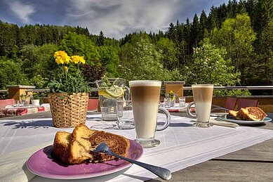 Kaffee und Kuchen auf dem Balkon mit Blick auf die Landschaft im Kinderhotel Bruckwirt in Oberösterreich.