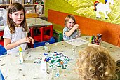 Zwei Kinder basteln und malen an einem Tisch mit Buntstiften und Glitzer im Kinderclub des Hotels Feldberger Hof.