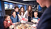 Sechs Kinder stehen beim Koch an der Theke, der frischen Kaiserschmarrn zubereitet im Familienhotel Allgäuer Berghof.