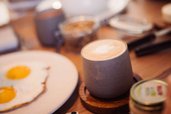 Frühstückstisch mit Cappuccino, Spiegelei und Müsli im Familienhotel Alpenhof Dolomit Family.