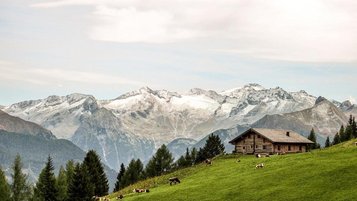 Almruhe nahe dem Hotel Sonngastein im Salzburger Land mit grüner Wiese, Berghütte und weitem Blick auf die Alpen.