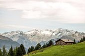 Almruhe nahe dem Hotel Sonngastein im Salzburger Land mit grüner Wiese, Berghütte und weitem Blick auf die Alpen.