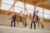Reiten mit Spaß: Zwei Kinder zeigen stolz ihre Balanceübungen im Familienhotel Friedrichshof.