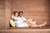 Eltern genießen eine entspannte Auszeit im Wellnessbereich des Familienhotels Family Home Alpenhof in gemütlicher Holz-Atmosphäre.