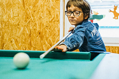 Kleiner Junge spielt Billard im Happy-Club des Familienhotels Ottonenhof im Sauerland.