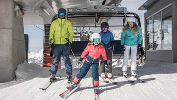 Winter im Salzburger Land: Familie fährt aus dem Skilift raus. Und los geht der Skispaß!