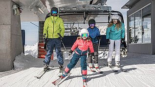 Winter im Salzburger Land: Familie fährt aus dem Skilift raus. Und los geht der Skispaß!