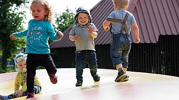 Vier Kinder hüpfen fröhlich auf der Hüpfburg im Landhuus Laurenz.