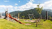 Naturspielplatz mit Rutschen und Nestschaukel im Familienhotel Almfamilyhotel Scherer in Tirol.