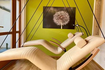 Im Familienhotel Ramsi laden stilvolle Schwebeliegen in einem gemütlichen Ruheraum mit warmem Licht und Naturakzenten zum Entspannen ein