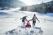 Eltern haben mit ihrem Kind viel Spaß beim Rodeln in Seefeld Tirol im Familienhotel Das Kaltschmid. 