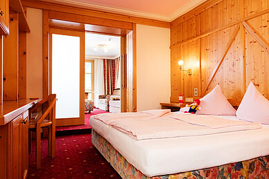 Gemütliches Schlafzimmer mit einem Doppelbett und direktem Durchgang in den Wohnbereich im Wellness- & Familienhotel Egger in Saalbach Hinterglemm.