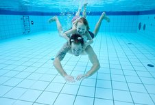 Vater und Tochter tauchen gemeinsam im Pool des Familienhotels Das Bayrischzell