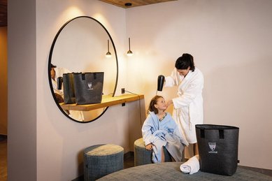 Mutter föhnt im Bademantel ihrer Tochter im Bademantel im Wellnessbereich des Familienhotels Kindl die Haare