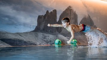 Ein Junge springt mit voller Freude ins Wasser und erlebt pures Badevergnügen im Alpenhof Dolomit Family in Südtirol