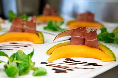 Vorspeise mit Melone und Parma Schinken angerichtet auf einem weißen Teller im Lärchenhof in Tirol