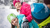 Familie tobt im Schnee im Winterurlaub im Salzburger Land.