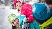 Familie tobt im Schnee im Winterurlaub im Salzburger Land.