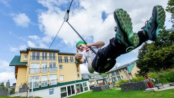 Kind schwingt mit der Schaukel über die Wiese vor dem Hotel Engel im Schwarzwald