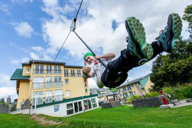 Kind schwingt mit der Schaukel über die Wiese vor dem Hotel Engel im Schwarzwald