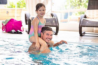 Vater und Tochter planschen im Hallenbad des Familienhotels Adler in Tirol.