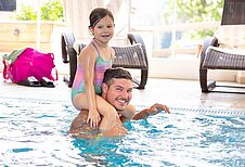 Vater und Tochter planschen im Hallenbad des Familienhotels Adler in Tirol.