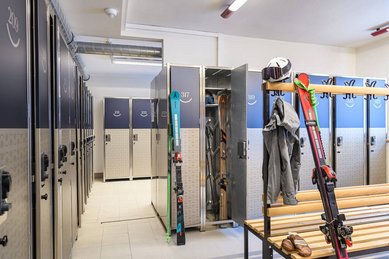 Skiraum des Zauchenseehofs mit nummerierten Spinden, aufgehängter Skiausrüstung und Sitzbank zum An- und Ausziehen.