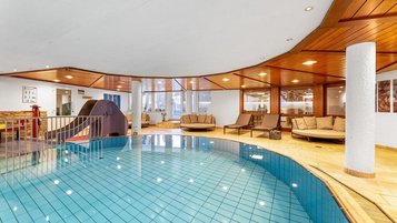 Hallenbad mit großzügigem Pool, Holzdecke und Ruheliegen im Wellnessbereich des Hotel Engel im Schwarzwald
