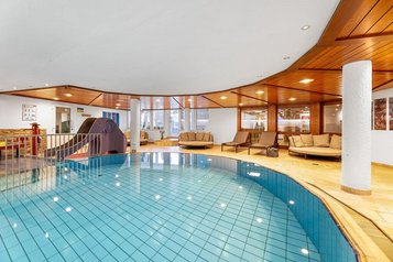 Hallenbad mit großzügigem Pool, Holzdecke und Ruheliegen im Wellnessbereich des Hotel Engel im Schwarzwald