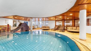 Hallenbad mit großzügigem Pool, Holzdecke und Ruheliegen im Wellnessbereich des Hotel Engel im Schwarzwald