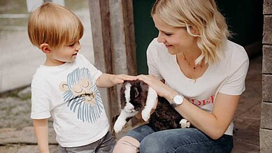 Mutter streichelt gemeinsam mit ihrem Kind einen Hasen im Kleintierbereich des Habachklause Familien Bauernhof Resorts.