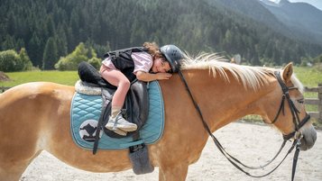 Kind liegt entspannt auf einem Haflinger im Familienhotel Kindl.